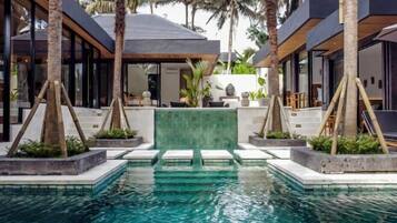 A modern pool area with clear water, surrounded by palm trees and contemporary architecture.