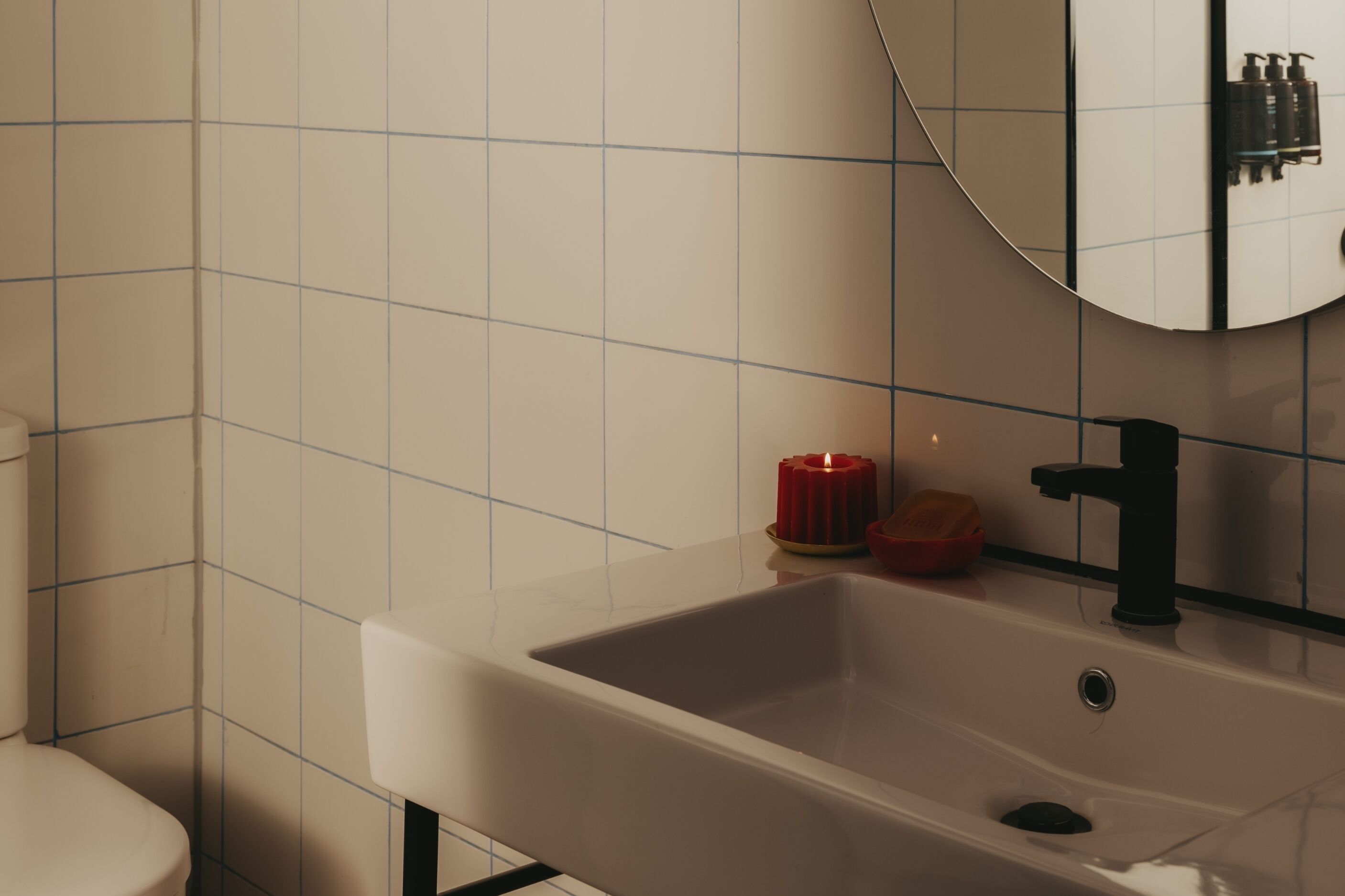 Un baño con lavamanos blanco, un espejo y un inodoro.