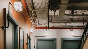 A hallway with three doors, each marked with a number. The walls are painted in two colors, and the floor has a patterned carpet. - Brassbell | DT | Hannaux | Tahrir Sq (Cairo)