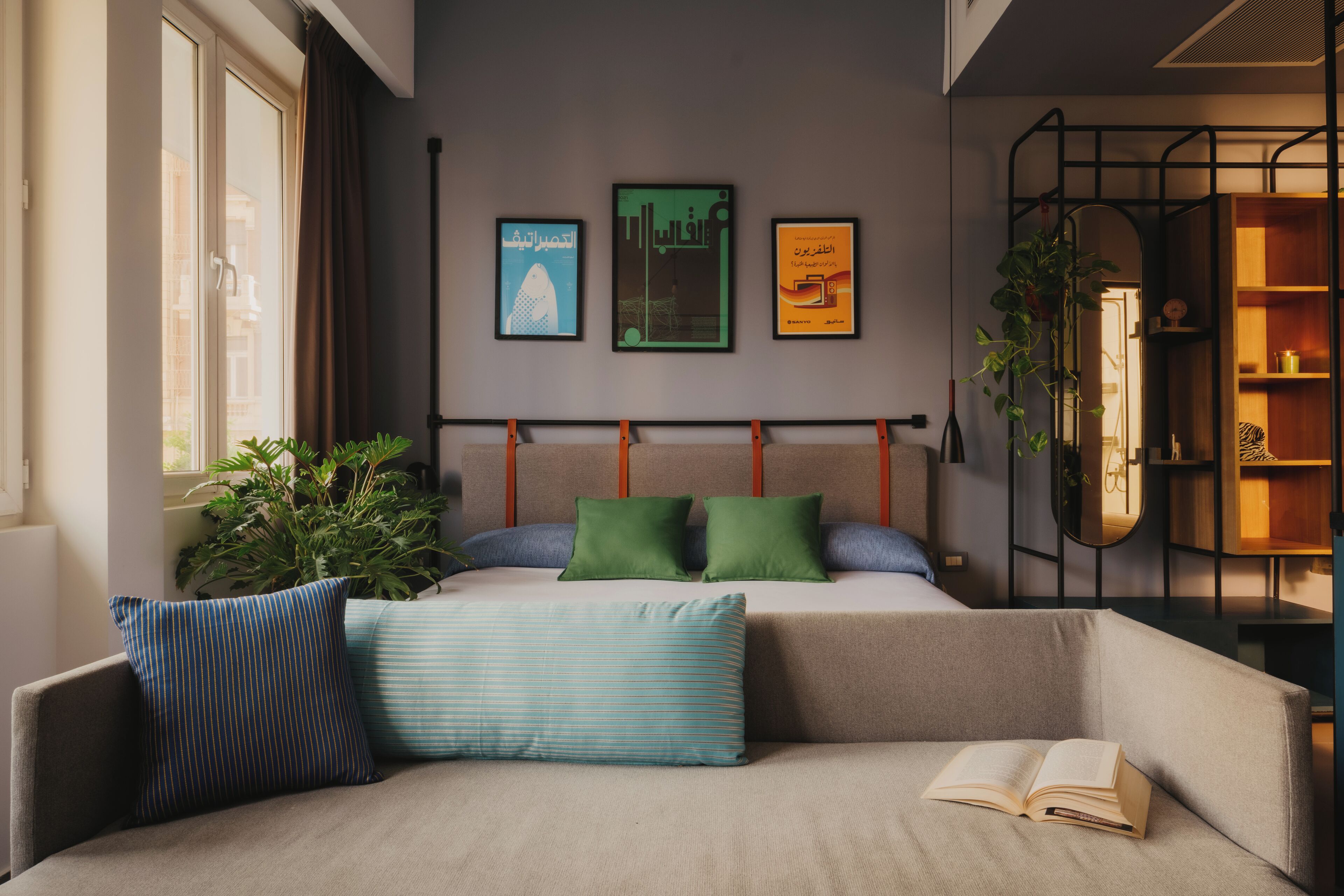 Un dormitorio moderno con una cama, una zona de lectura con sofá y un ventanal grande.