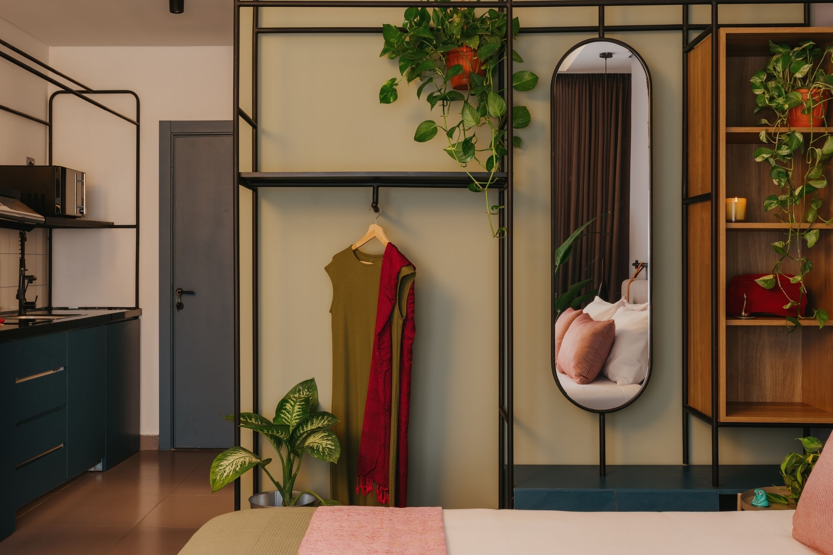 Une chambre à coucher comprenant un lit, une table de chevet, un miroir, une armoire et une plante suspendue.