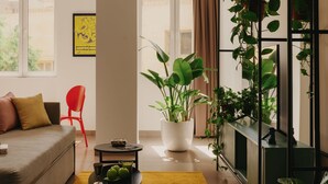 A modern living room with a sofa, a red chair, a coffee table, and a potted plant. - Brassbell | DT | Hannaux | Tahrir Sq (Cairo)