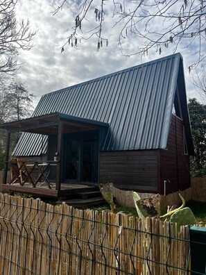 A small, rustic cabin with a sloped metal roof, a wooden deck, and a fenced yard. - Akorya Bungalov (Ardeşen)
