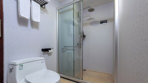 Une salle de bain équipée de toilettes, d’une douche à parois de verre et d’un porte-serviettes.