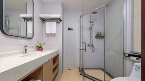 Une salle de bain moderne avec une douche à parois de verre, un lavabo doté d’un plan de toilette en marbre et des toilettes.