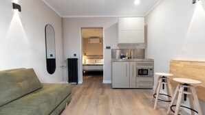 Un espace de vie compact comprenant un canapé, une kitchenette et un petit coin repas.