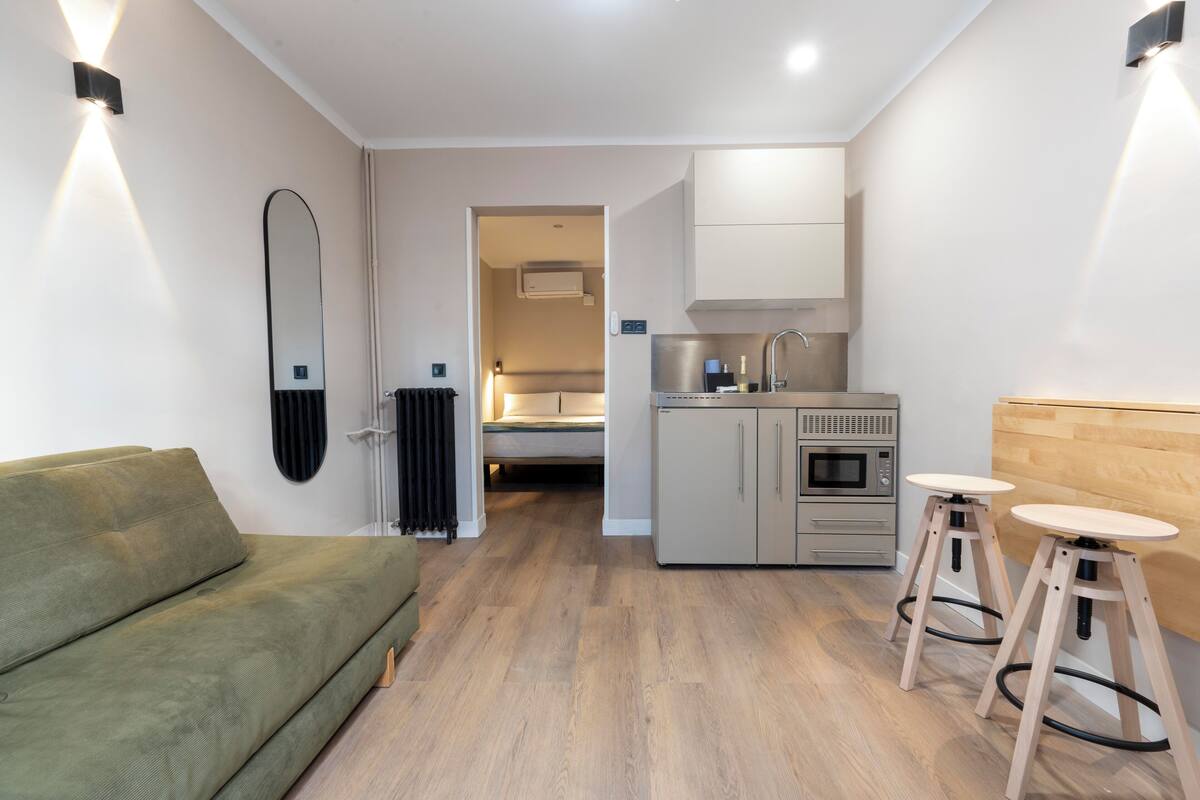 Een compacte woonruimte met een bank, kitchenette en een klein eetgedeelte.