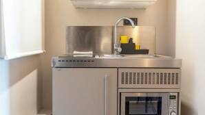 Une cuisine compacte équipée d’un évier en acier inoxydable, d’un four à micro-ondes et d’un four encastré.