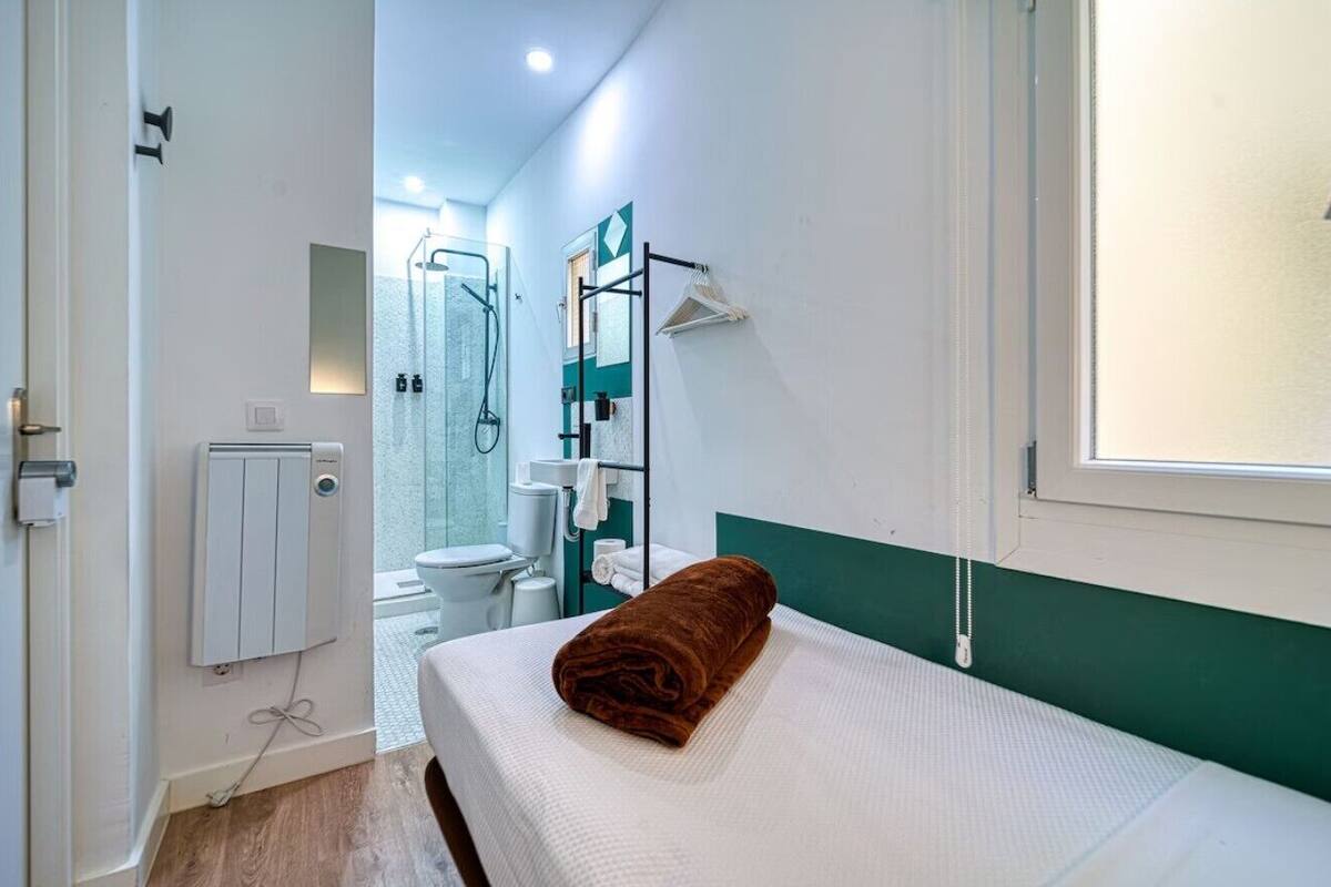 Een hotelkamer met een bed, een badkamer met douche en uitzicht op zee.