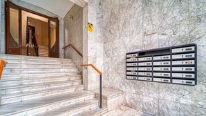 Un escalier en marbre avec une rampe métallique et une boîte aux lettres fixée au mur.