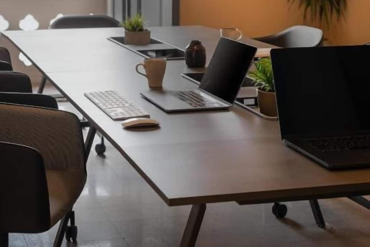 Een modern kantoor met een lange tafel, laptops en stoelen.