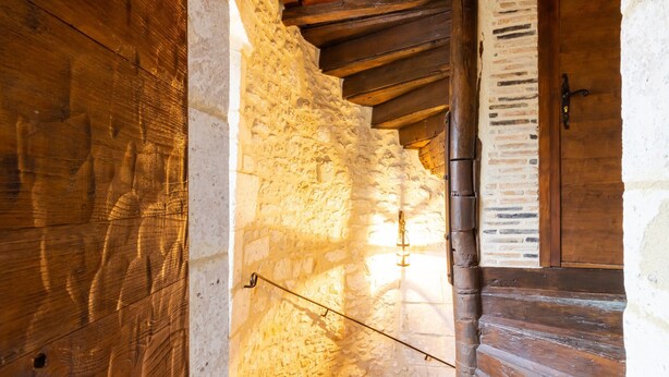 Una rústica escalera de madera con paredes de piedra y una puerta de madera.