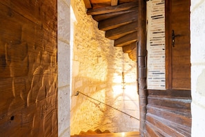 Una rústica escalera de madera con paredes de piedra y una puerta de madera.