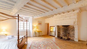 Un dormitorio con cama con dosel, chimenea y alfombra estampada.