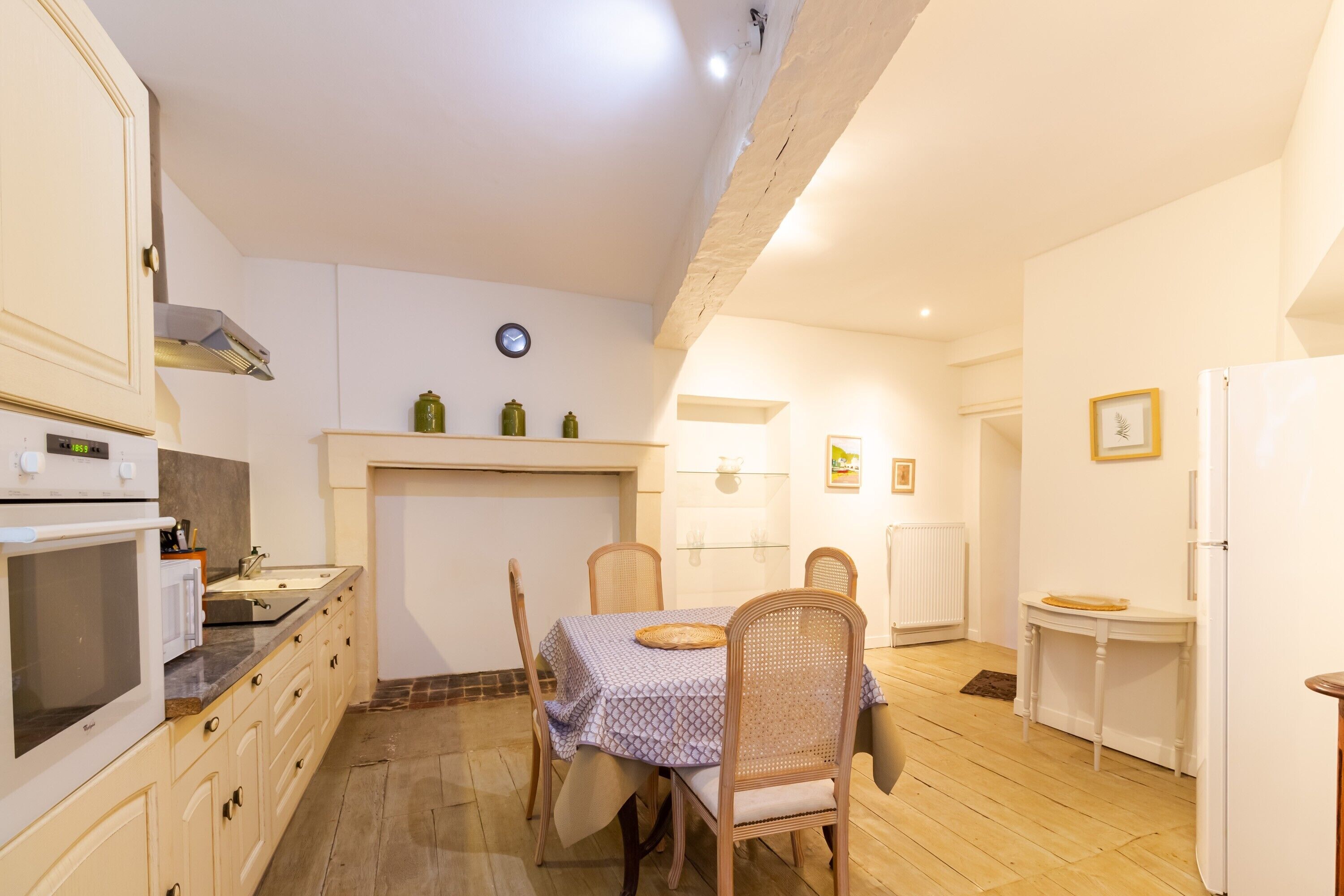 A kitchen with a dining table, chairs, a microwave, and a refrigerator.