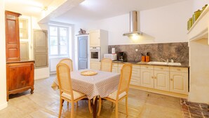Una cocina con una mesa de comedor, sillas, armarios, una estufa y un microondas.