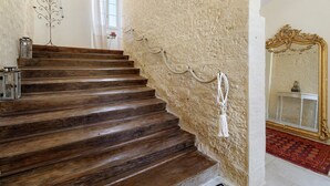 A wooden staircase with a textured wall, a decorative metal piece, and a mirror with an ornate frame. - Guest Room “Blue Room” in the Château (Saint-Privat des Prés)