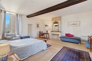 Un dormitorio con cama, sofá, escritorio, silla, lámpara y chimenea.