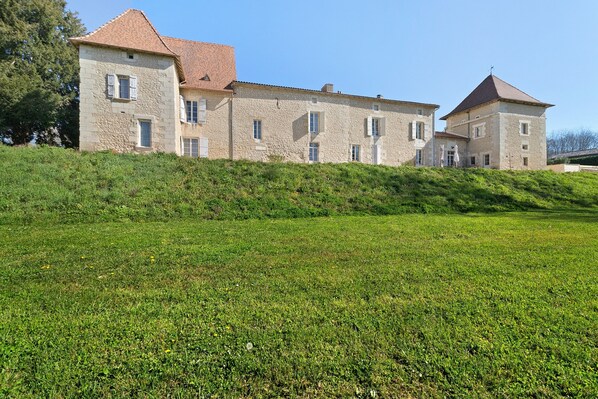 A stone building with multiple windows and a sloped roof.