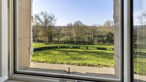Blick aus dem Fenster auf eine Wiese mit Bäumen und einem Kiesweg.