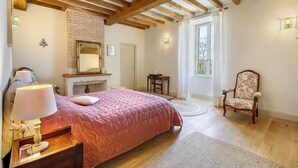 Ein Schlafzimmer mit Bett, Stuhl, Nachttisch, Kamin und Fenster.