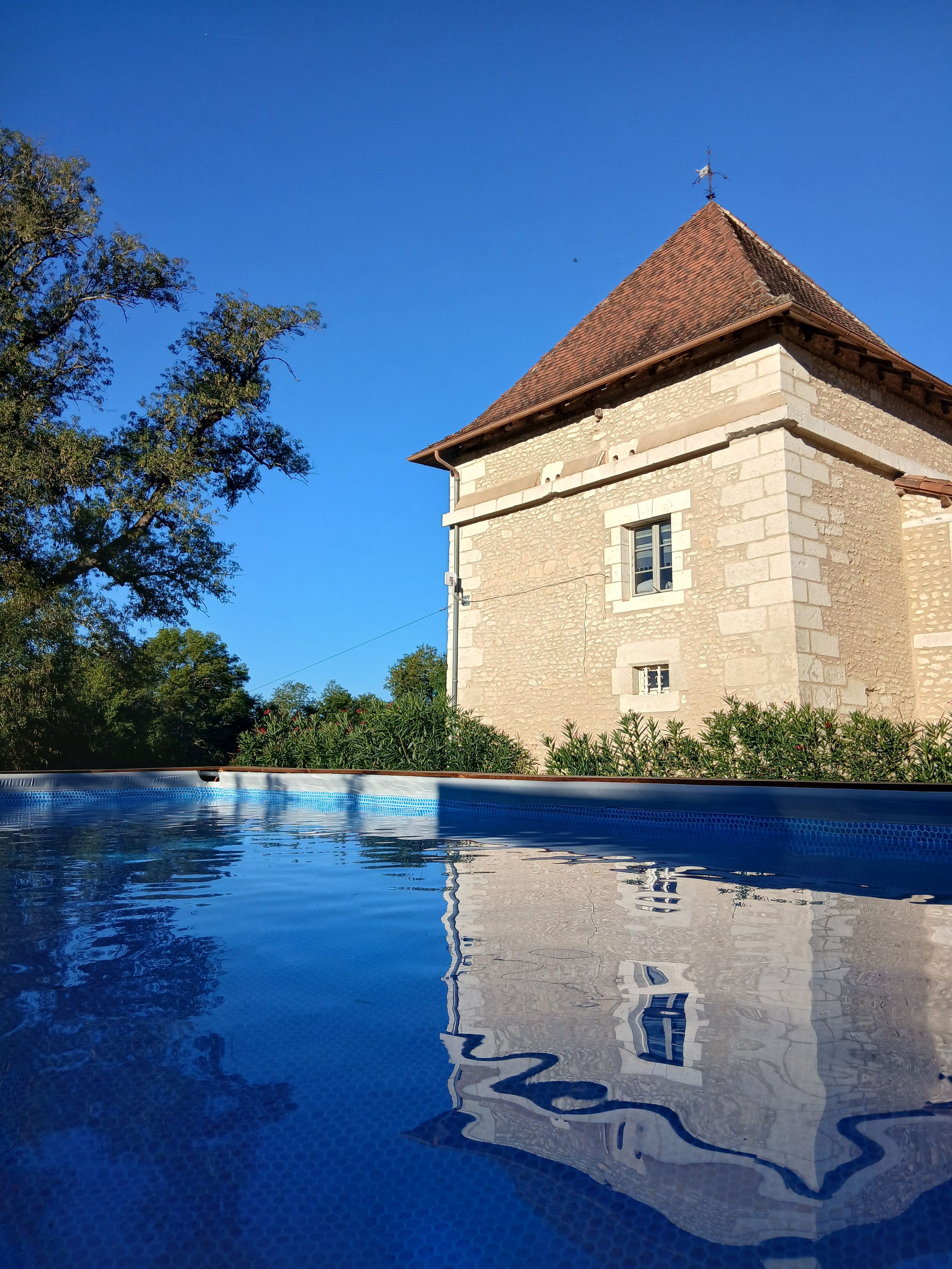Ein Steinhaus mit einem Ziegeldach und einem Schwimmbecken davor.