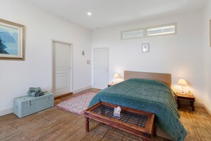 A bedroom with a wooden bed, two bedside tables with lamps, a small wooden chest, and a framed picture on the wall. - Guest Room “Green Room” in the Castle (Saint-Privat des Prés)