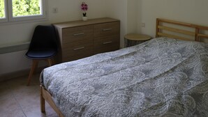 A bedroom with a bed, a dresser, a chair, a small table, and a hanging light fixture. - Apartment between lake and mountains, near resort (Chorges)