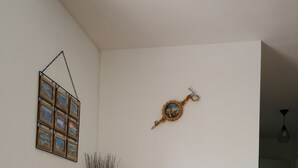A living room with a TV on a white stand, a lamp, and a decorative wall piece. - Apartment between lake and mountains, near resort (Chorges)