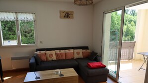 A modern living room with a sectional sofa, a wooden coffee table, and a sliding glass door leading to a balcony. - Apartment between lake and mountains, near resort (Chorges)