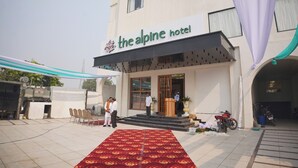Hotel de montaña con alfombra roja que lleva a la entrada, mesas al aire libre y una motocicleta estacionada afuera.