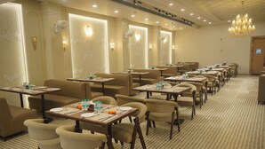 Un comedor de hotel con varias mesas y sillas, equipado con botellas de agua y servilletas.