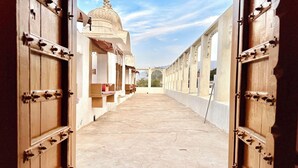 Un pasillo con puertas de madera abiertas que dan a un edificio con estructura de cúpula.