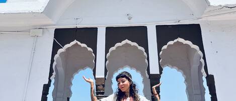 A person standing in front of a white building with arches and a dome.
