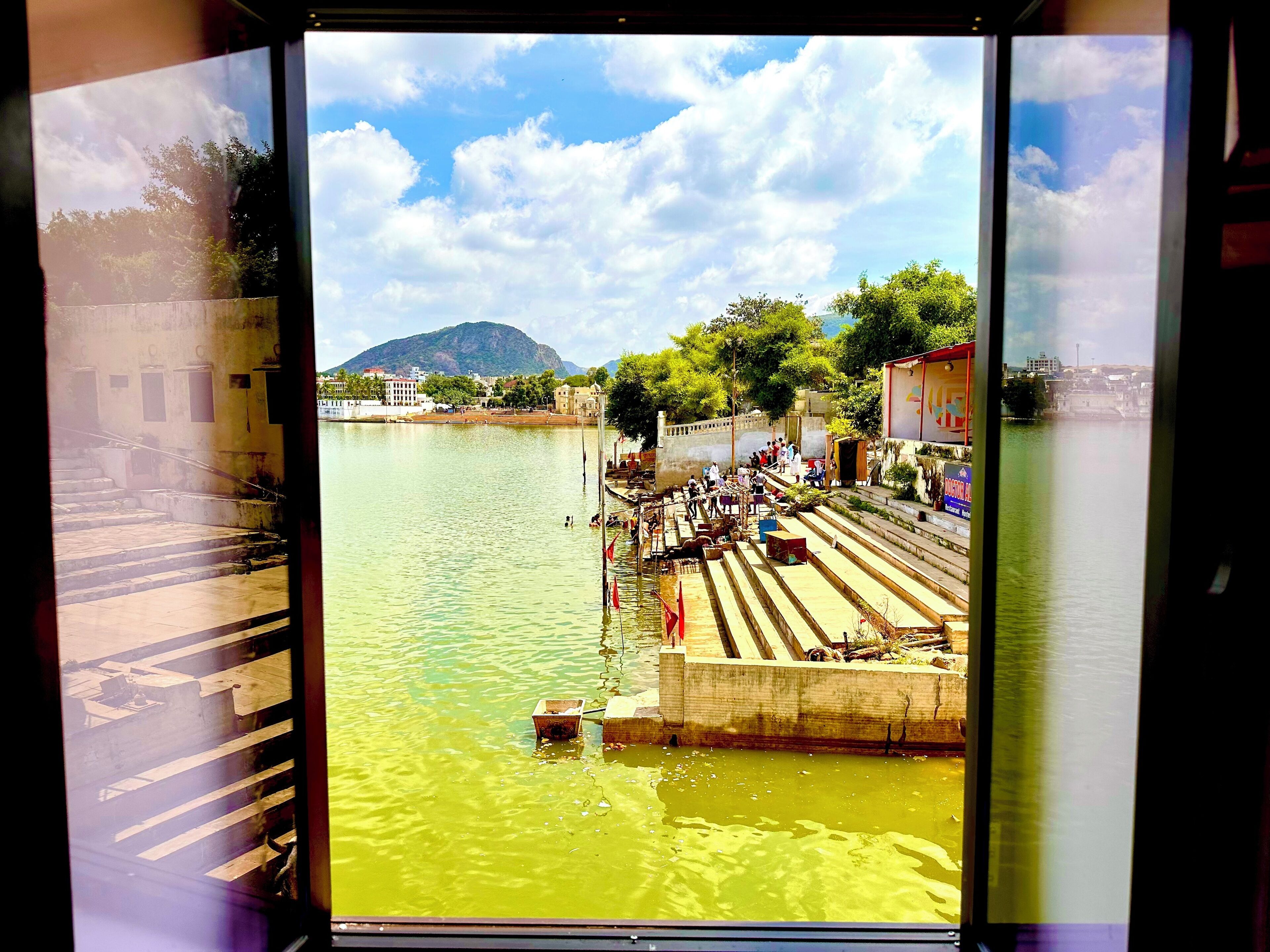 Vista di un fiume con gradini che scendono verso l'acqua, circondato da edifici e alberi.