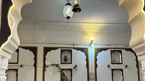 Un interior tradicional con arcos ornamentados, un suelo con estampado y una mesa con sillas.