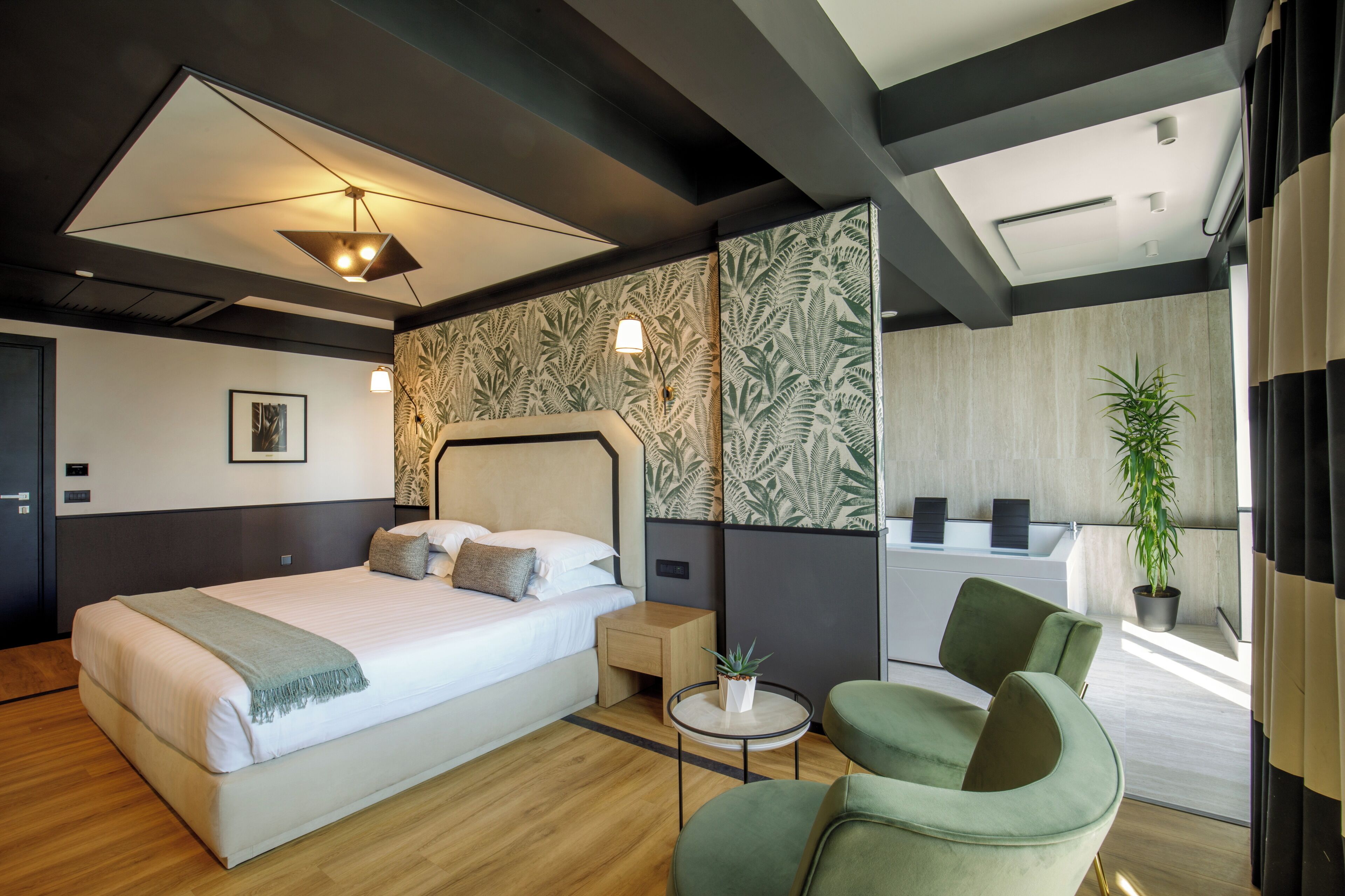 A modern hotel room with a large bed, a small side table, a green armchair, and a view of the bathroom.