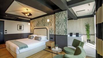 A modern hotel room with a large bed, a small side table, a green armchair, and a view of the bathroom.