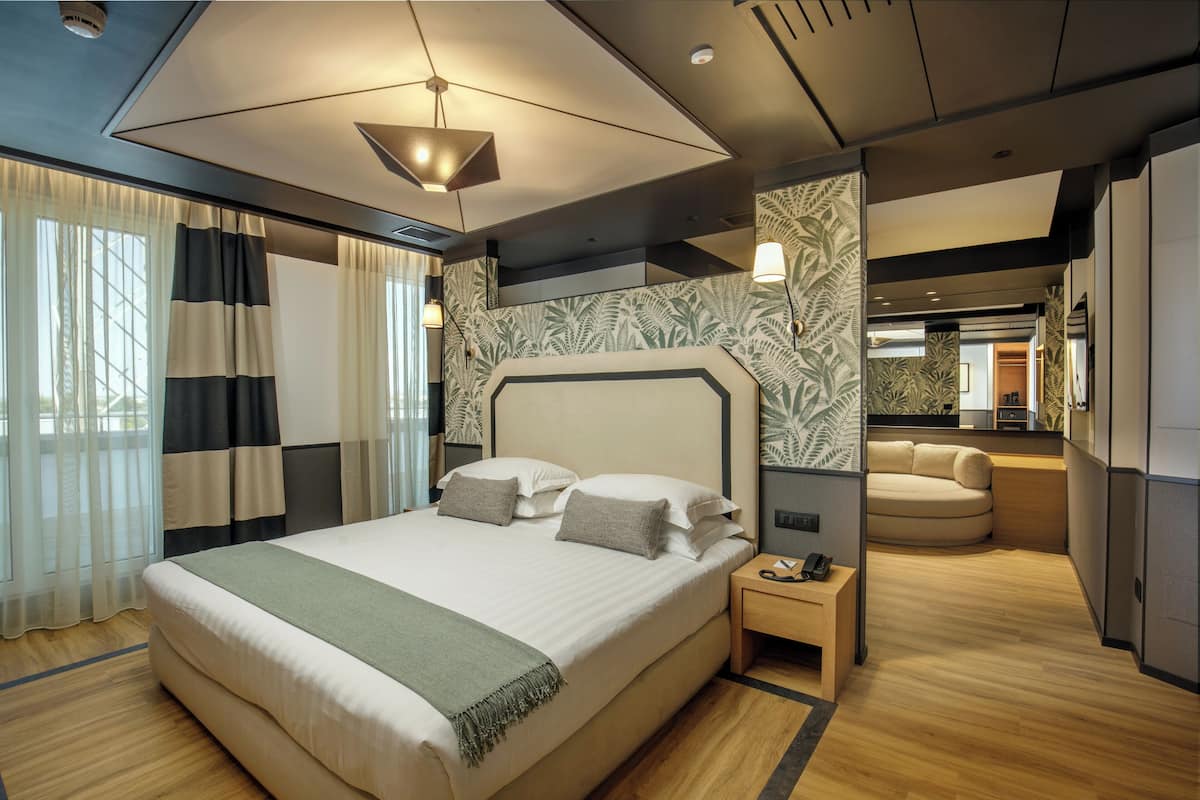 Una habitación de hotel moderna con una cama grande, una mesita de noche, un sofá y un pequeño rincón de descanso.