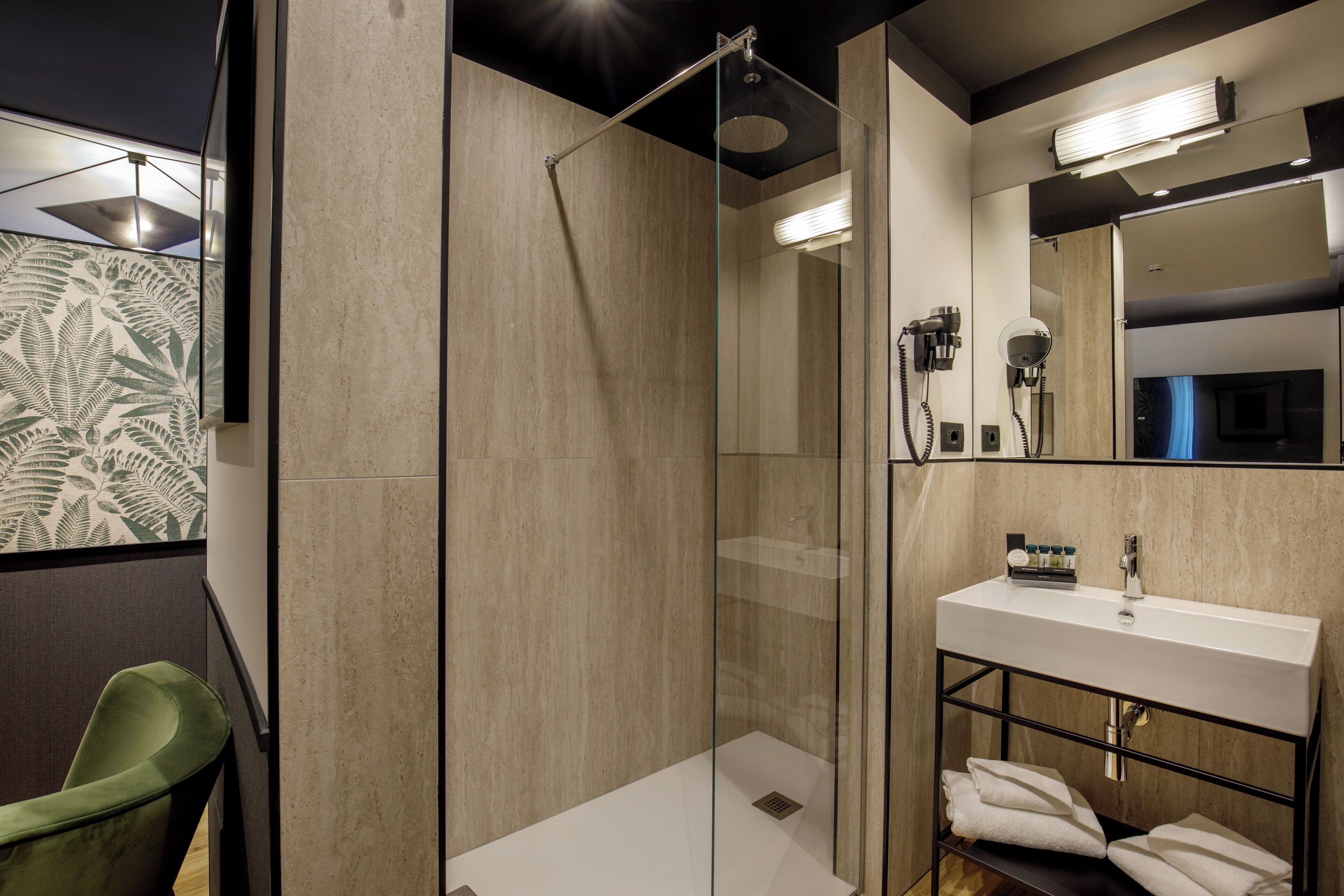 A modern bathroom with a glass-enclosed shower, a white sink, and a mirror above it.