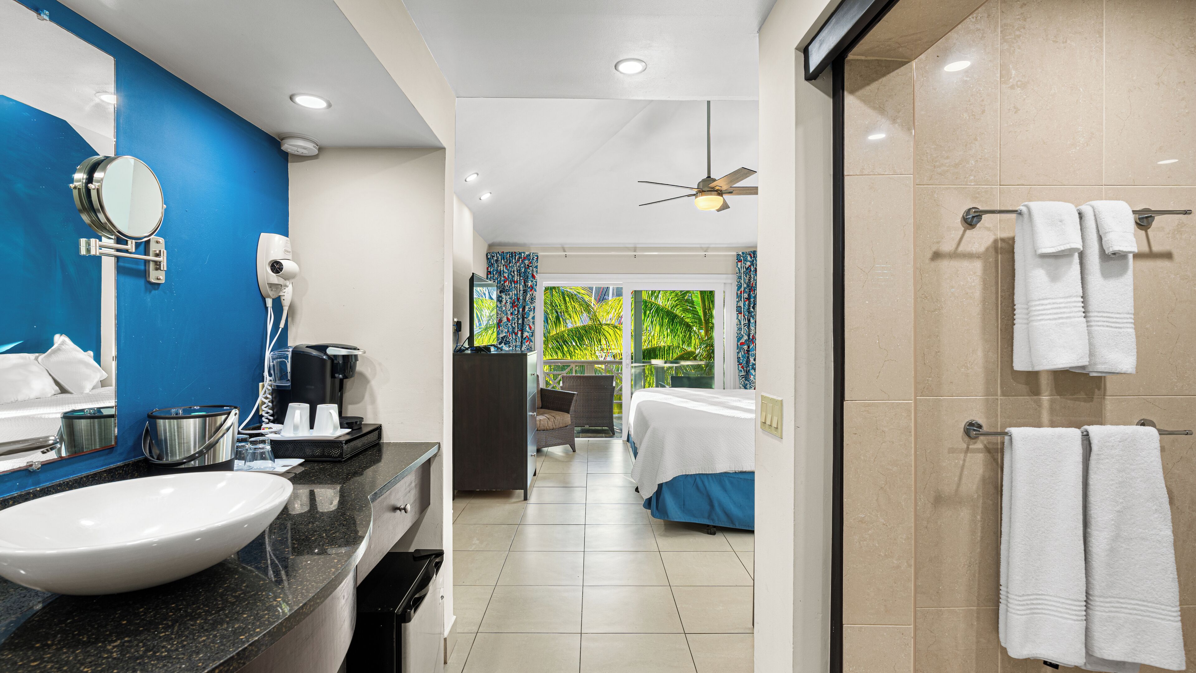 Un baño de hotel moderno con un lavamanos grande, espejo y zona de ducha con toallas.
