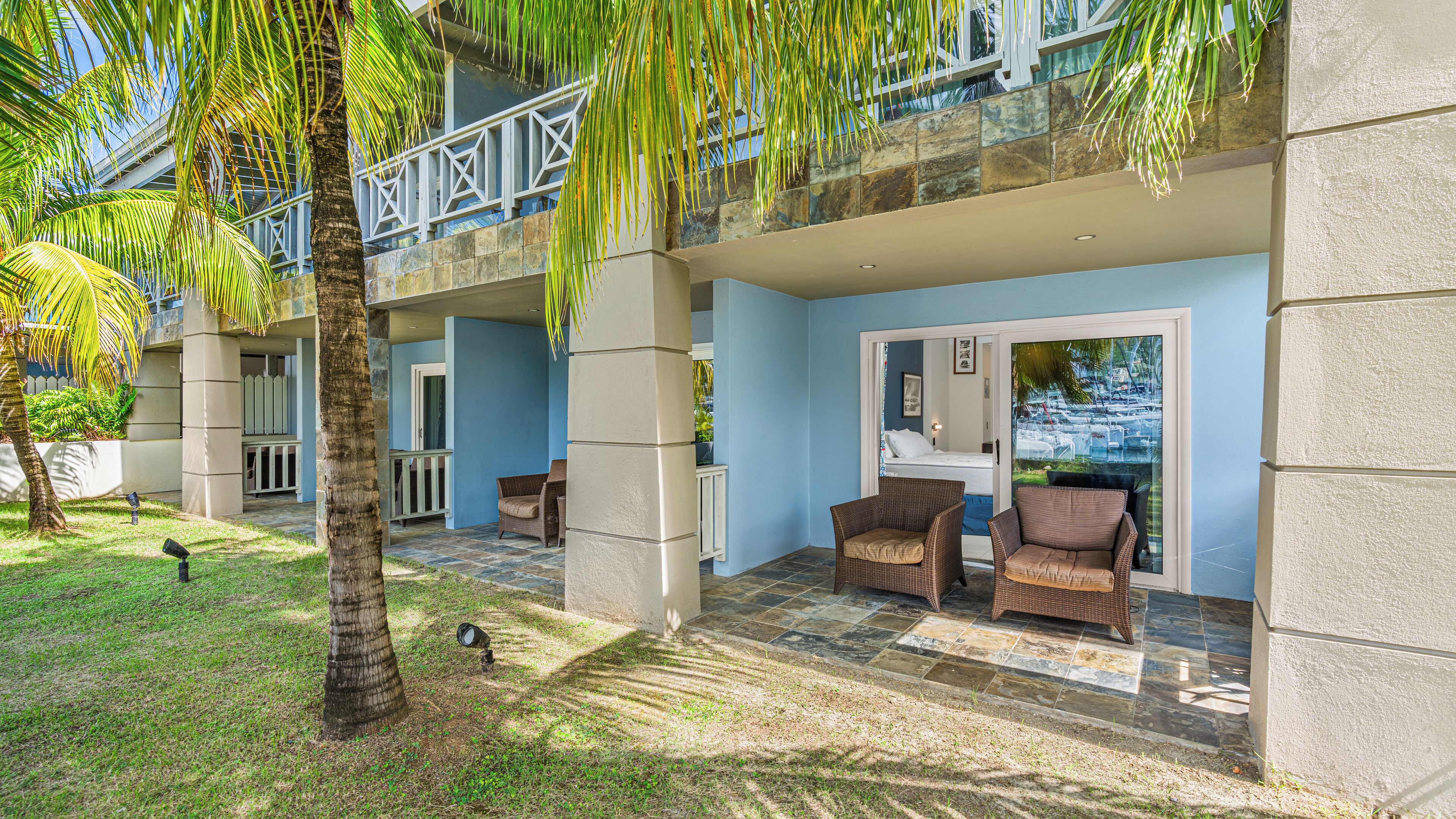 A hotel with a covered outdoor area, including wicker furniture and a view of the marina.
