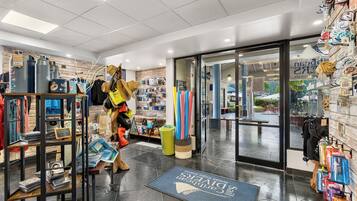 A store with shelves of bags and hats, a display of water bottles, and a view of the outside.