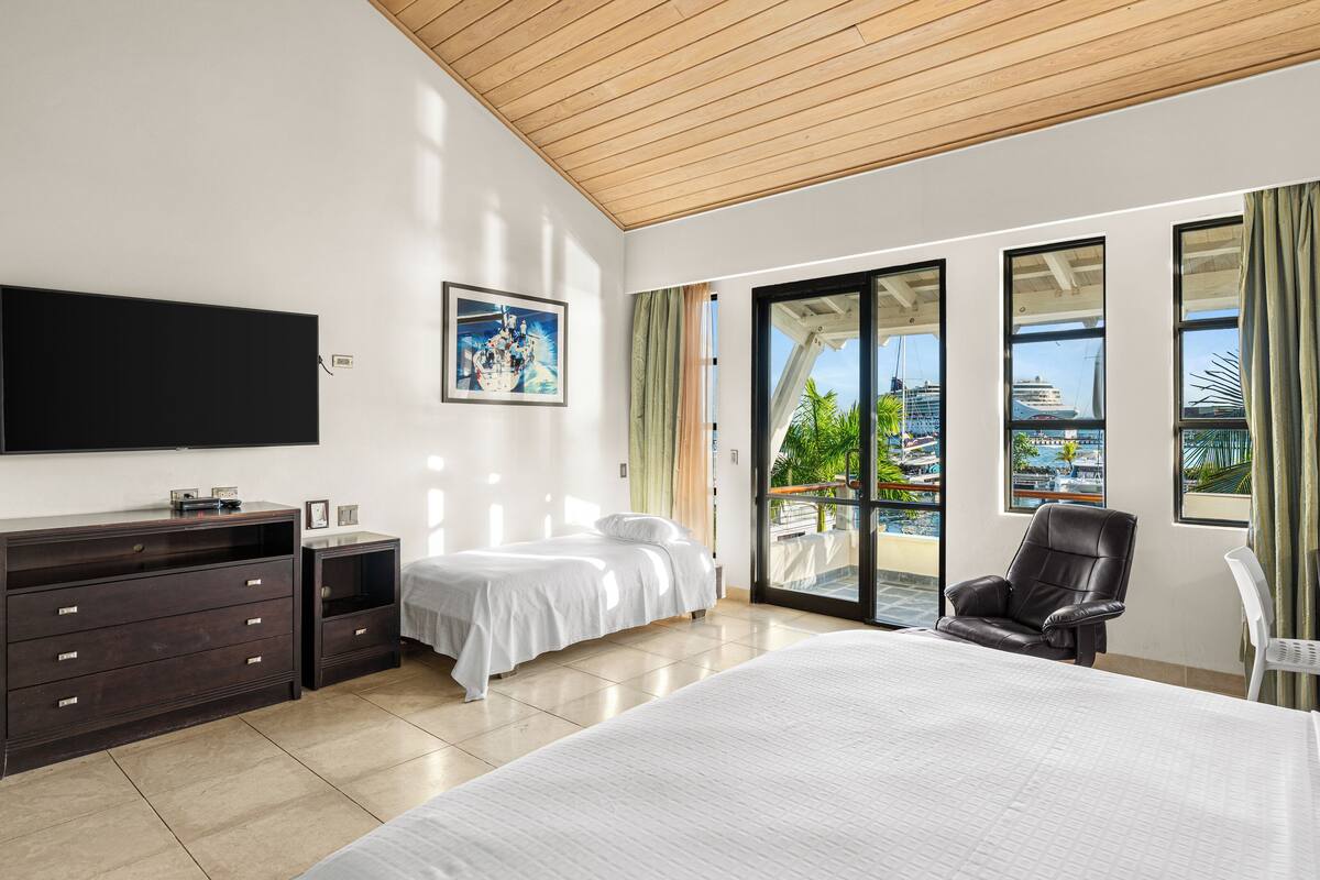 Camera d'albergo con un letto grande, una scrivania, una sedia, una televisione e un quadro appeso al muro.