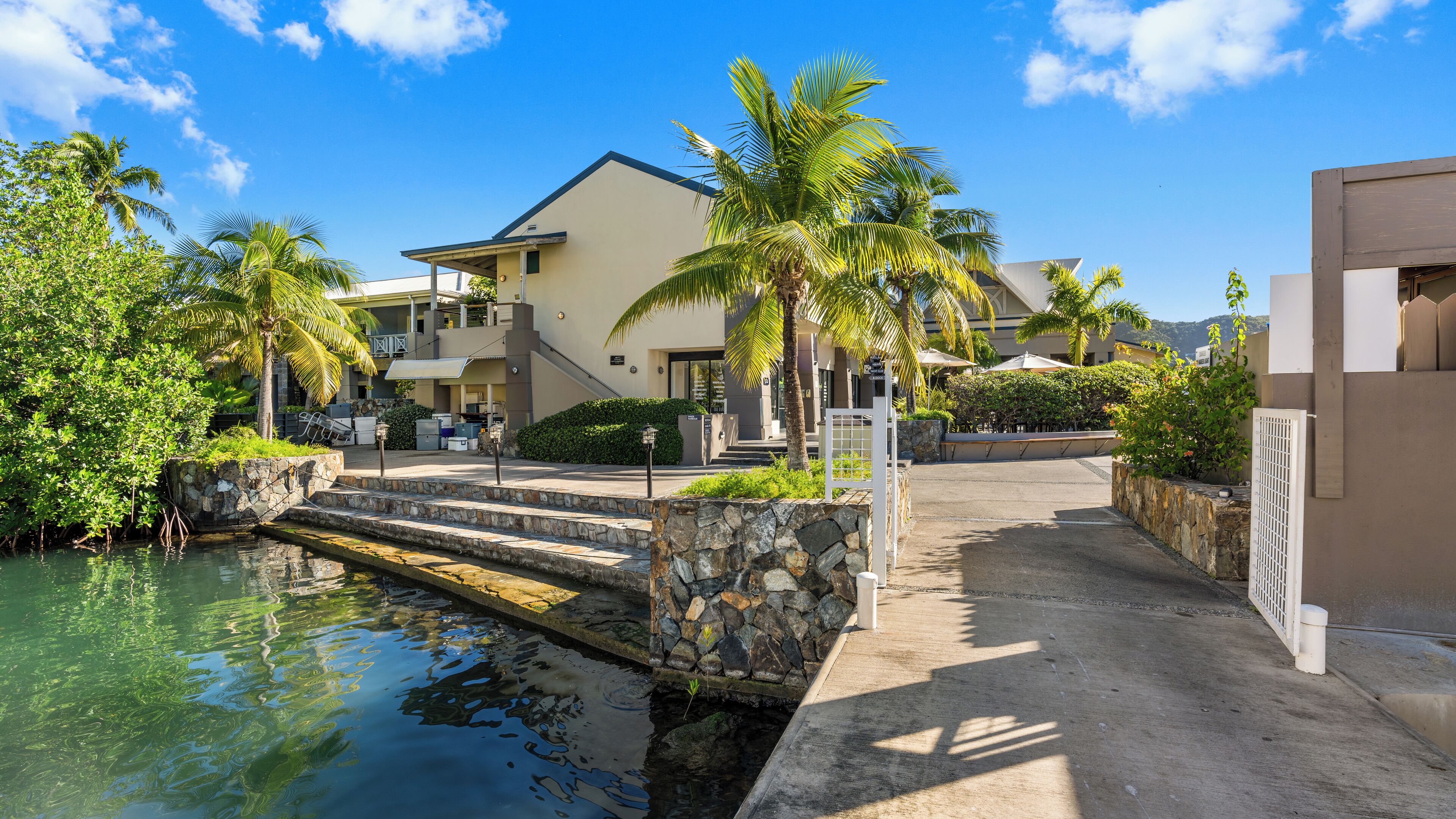 A resort with a pool, palm trees, and a stone pathway leading to the buildings.