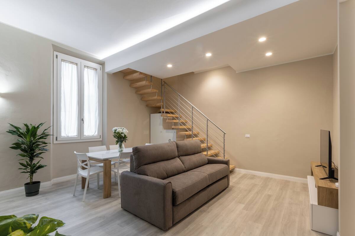 Un salon moderne avec un canapé, une table à manger et un escalier.