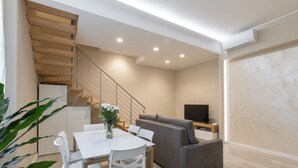 A modern living room with a staircase, a dining area, and a TV. - Orsini 98 Apartments by Mamo Florence (Florence)