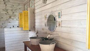 A rustic bathroom with wooden walls, a wooden bench, two white buckets, a mirror, and a yellow window shutter. - Lima Limón Eco Island - Panama (Bocas del Toro)