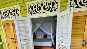 A room with a bed, white curtains, and wooden shutters. - Lima Limón Eco Island - Panama (Bocas del Toro)