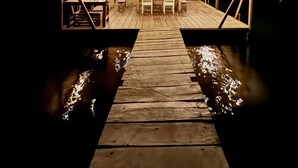 A wooden dock leading to a thatched-roof outdoor seating area with tables and chairs. - Lima Limón Eco Island - Panama (Bocas del Toro)